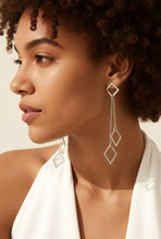 Load image into Gallery viewer, Close-up of a woman wearing long, dangling sterling silver drop earrings with a neutral background