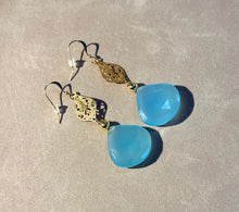 Load image into Gallery viewer, Pair of blue teardrop earrings with gold accents on a beige surface