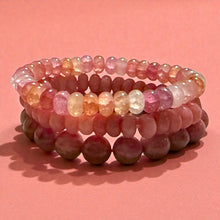 Load image into Gallery viewer, Stack of pink beaded bracelets on a pink background