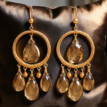 Load image into Gallery viewer, Gold earrings with teardrop-shaped gemstones on a dark fabric background