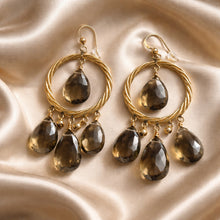 Load image into Gallery viewer, Gold hoop earrings with smoky quartz stones on a beige fabric background