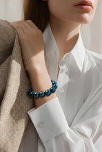 Load image into Gallery viewer, Person wearing a blue beaded bracelet on a plain background