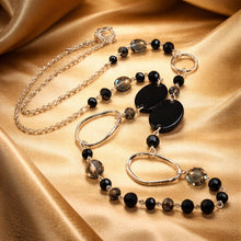 Load image into Gallery viewer, Necklace with black and silver beads on a gold fabric background