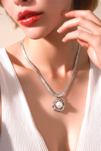Load image into Gallery viewer, A close-up lifestyle shot of a model wearing a silver-toned snake chain necklace with a circular flower pendant featuring a white pearl in sterling silver