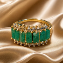 Load image into Gallery viewer, Gold ring with emeralds and white topaz on a gold fabric background
