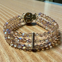 Load image into Gallery viewer, Multistrand beaded bracelet with gold clasp on a wooden surface
