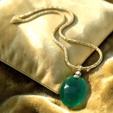 Load image into Gallery viewer, Gold necklace with a green pendant on a gold surface
