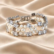Load image into Gallery viewer, A multi-strand pearl and crystal bracelet with a silver-toned clasp, displayed on a draped champagne satin fabric.
