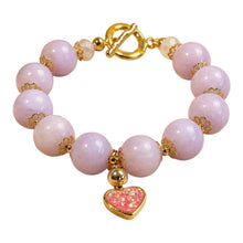 Load image into Gallery viewer, A beaded bracelet featuring light pink stone beads, gold-tone spacer details, a gold toggle clasp, and a dangling heart charm with pink glitter and a gold border, shown on a plain white background.
