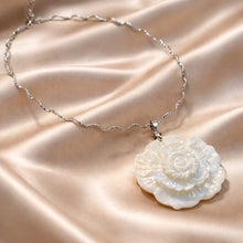 Load image into Gallery viewer, Necklace with a floral pendant on a beige fabric background
