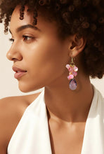 Load image into Gallery viewer, A close-up side profile of a woman with curly hair wearing a dangling earring. The earring features pink flower-like beads, a small gold-toned accent, and a teardrop-shaped purple stone at the bottom.
