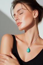 Load image into Gallery viewer, Woman wearing a black top and turquoise pendant necklace against a neutral background

