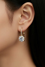 Load image into Gallery viewer, A close-up of a model's ear wearing a gold huggie hoop earring with a large clear round-cut gemstone and a small row of pavé-set stones along the upper hoop.
