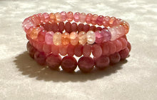 Load image into Gallery viewer, Stack of pink beaded bracelets on a light background
