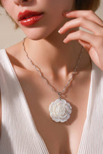 Load image into Gallery viewer, Close-up of a necklace with a floral pendant worn by a person in a white top.
